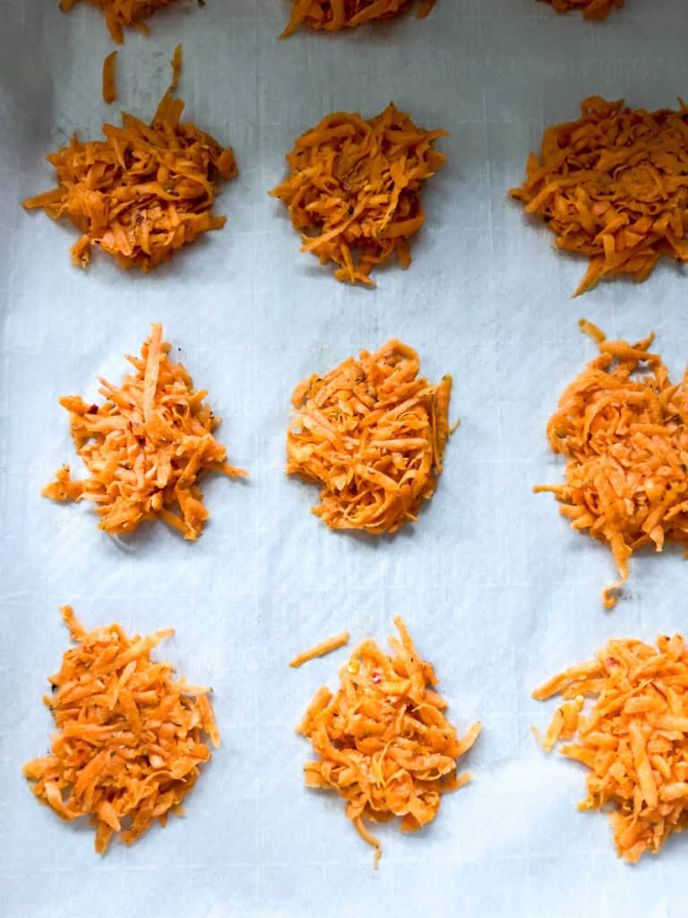 Shredded sweet potato piles on a baking sheet ready to bake