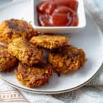 Crispy sweet potato hash brown circles on a plate with a side of ketchup