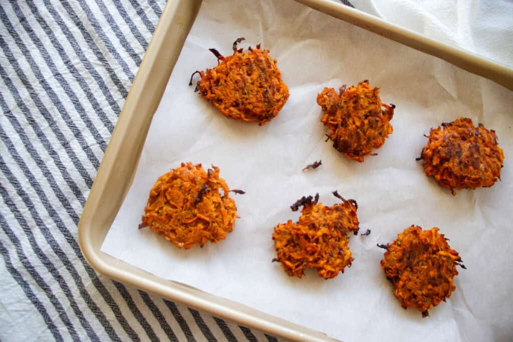 Crispy out of the oven hot honey sweet potato hash brown circles on a baking sheet