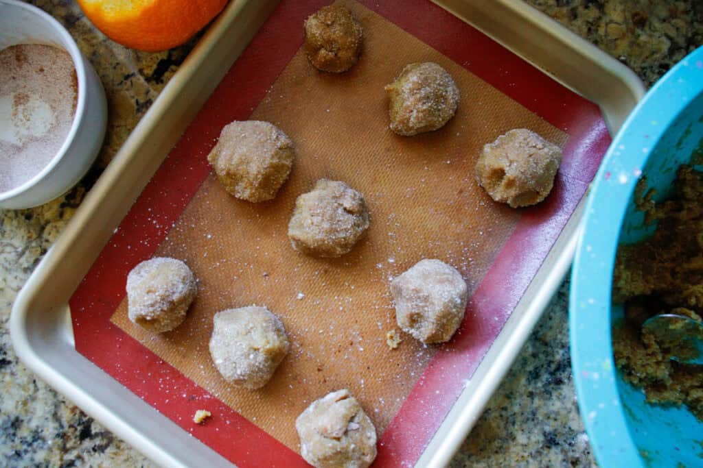 raw orange almond flour cookie dough balls on a baking sheet ready to put in the oven