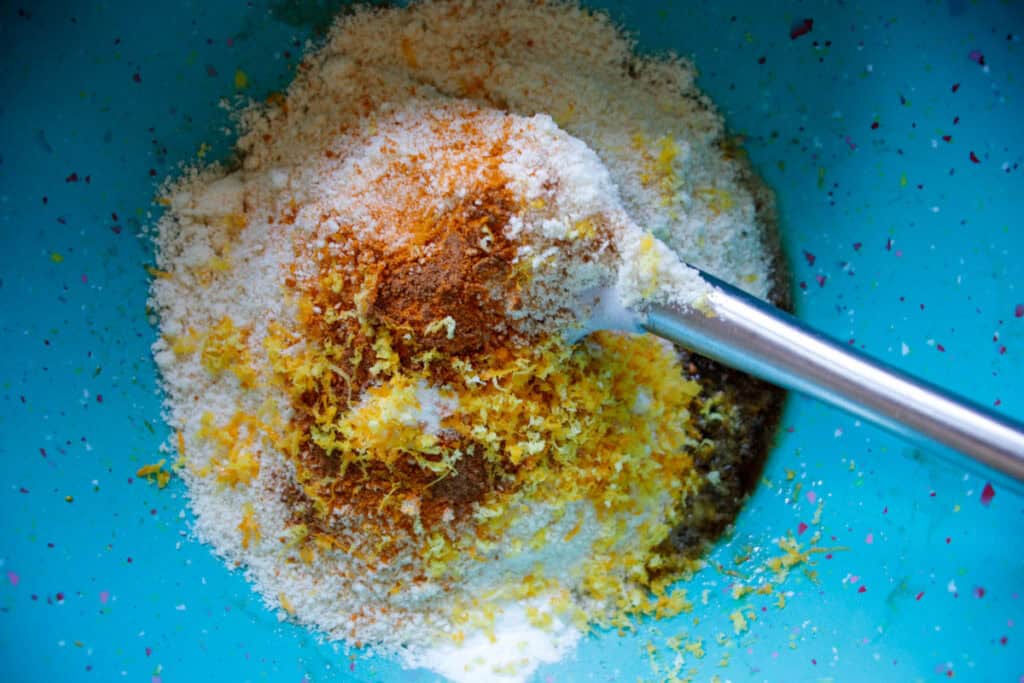 Turquoise mixing bowl with dry cookie ingredients flour, cinnamon and orange zest