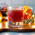 Sparkling orange pomegranate drink for the holidays on a tray with christmas lights