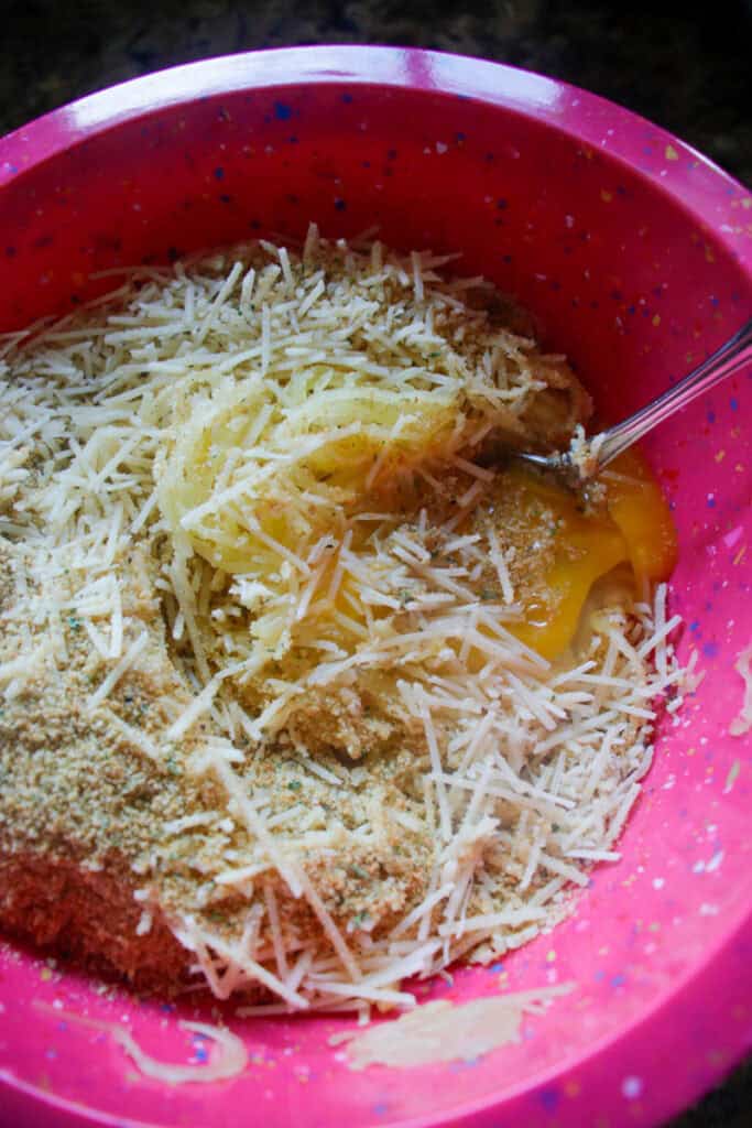 spaghetti squash, cheese, eggs and bread crumbs in a bowl