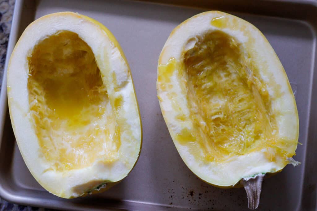 spaghetti squash halves drizzled in oil on baking sheet