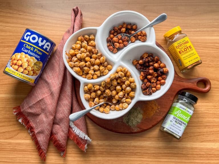 Overhead of crispy chickpeas in a bowl and seasoning bottles