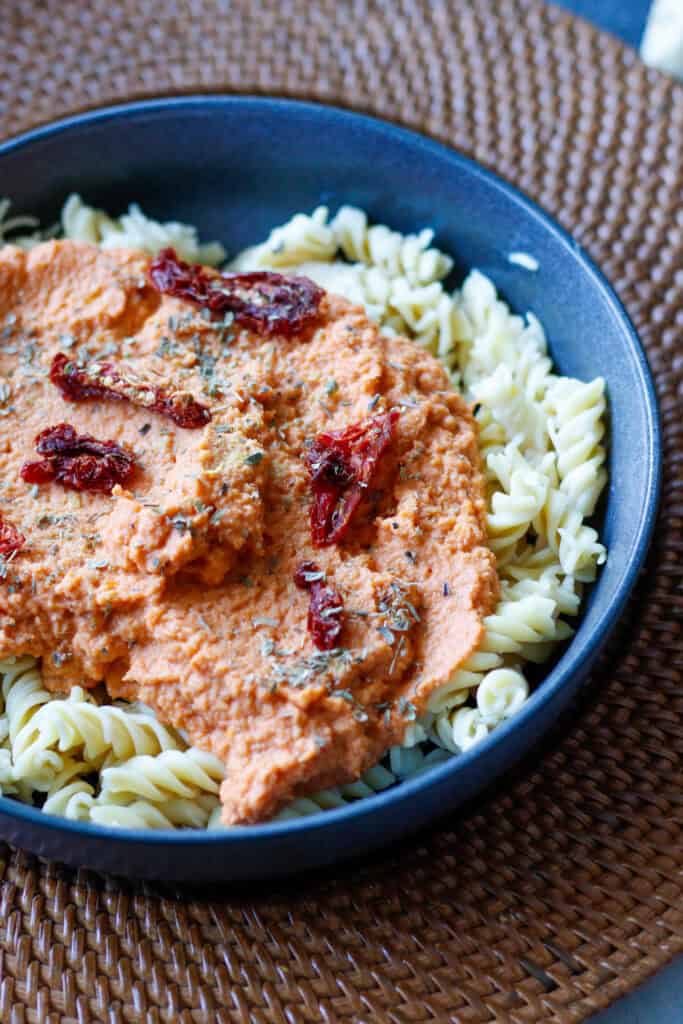Easy plant-based cauliflower pasta sauce over a bed of Banza pasta noodles garnished with sun-dried tomatoes.