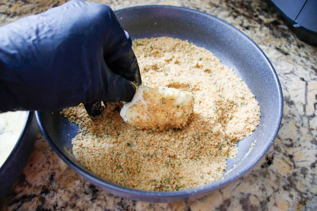 Person rolling cauliflower in breading