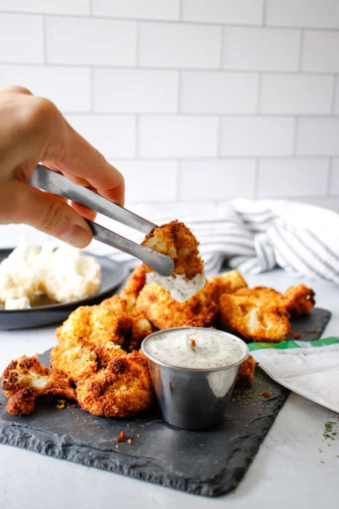 person dipping healthy cauliflower bites into creamy italian dressing