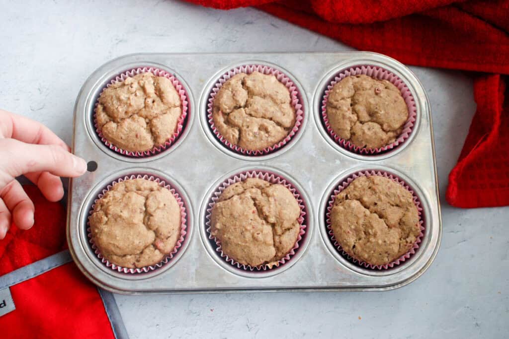 person placing muffin pan on countertop