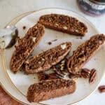 Chocolate pecan biscotti with chunks of pecans, served on a white plate, perfect for coffee or tea. A delicious, crunchy treat made with rich chocolate and toasted pecans.