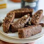 Rich chocolate biscotti with chopped nuts on a white plate.