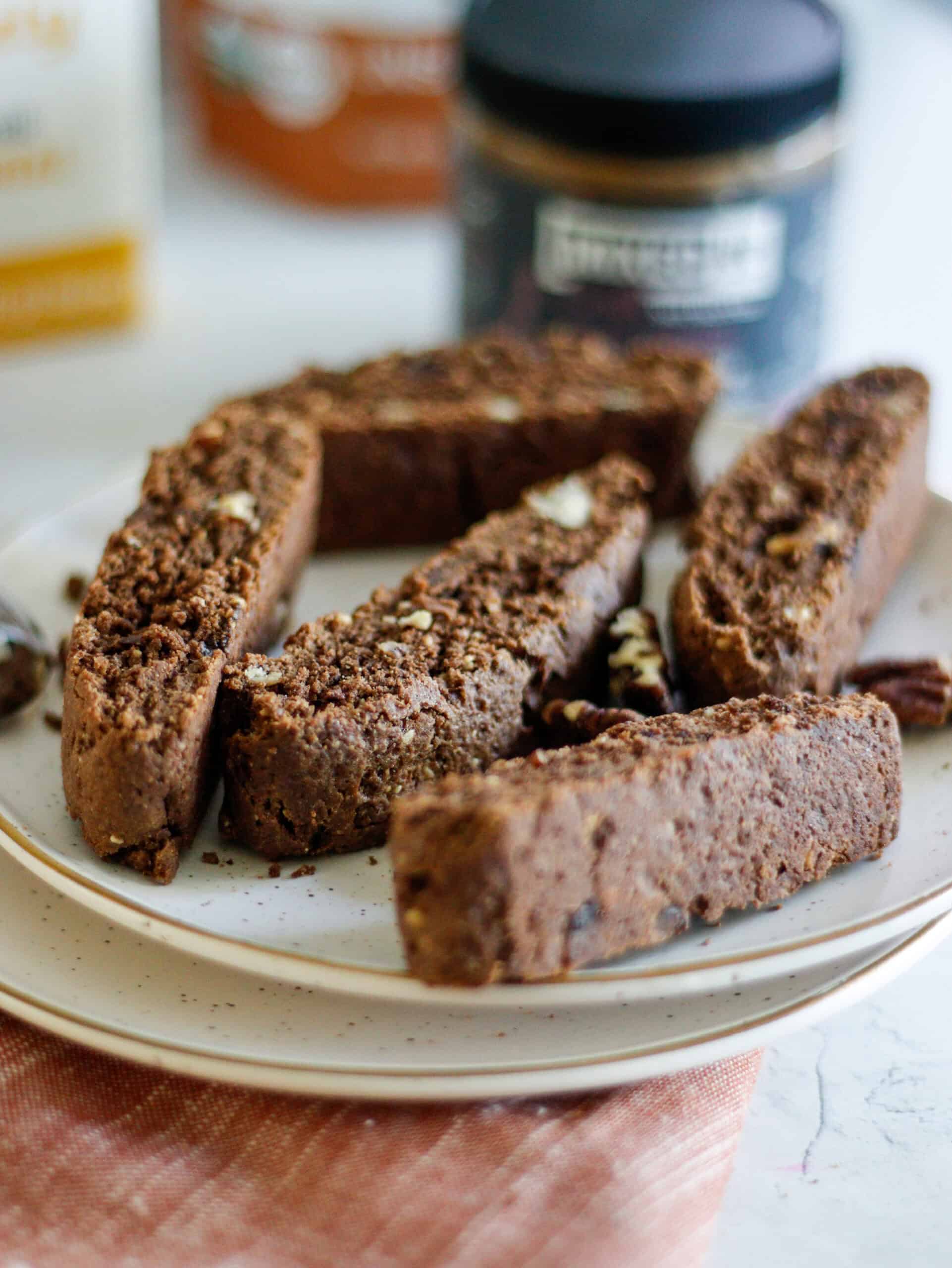Rich chocolate biscotti with chopped nuts on a white plate.