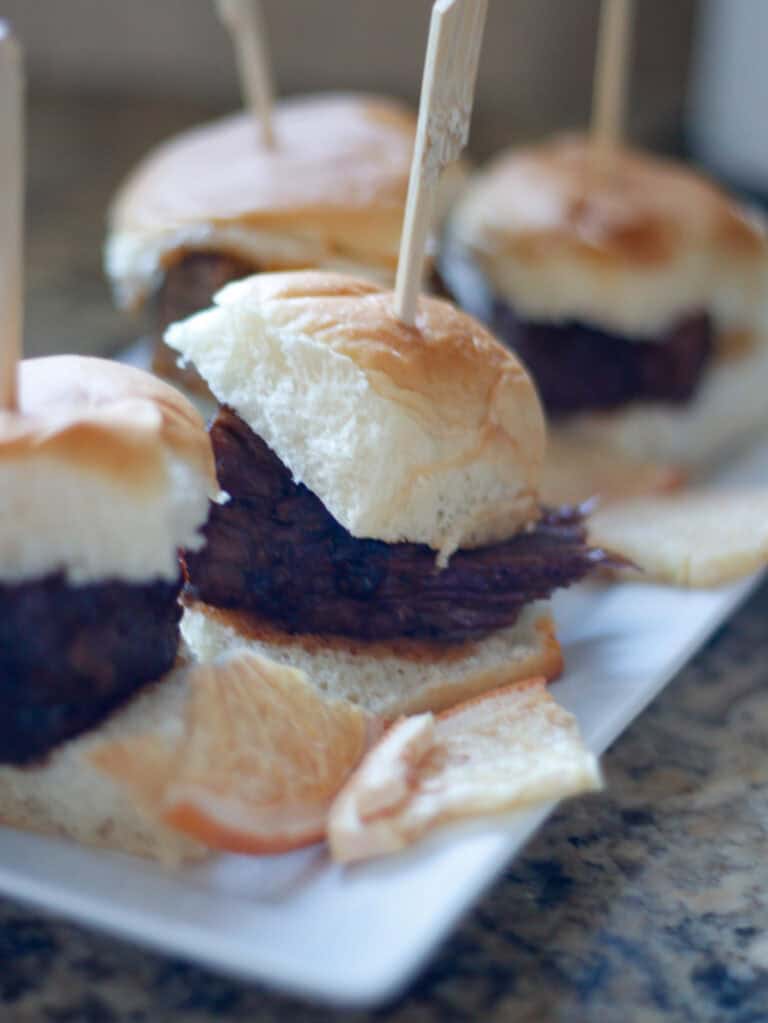 Juicy beef sliders with toasted buns, melted cheese, and crispy bacon on a serving platter, perfect for tasting events and appetizer platters, showcasing delicious gourmet appetizer ideas.