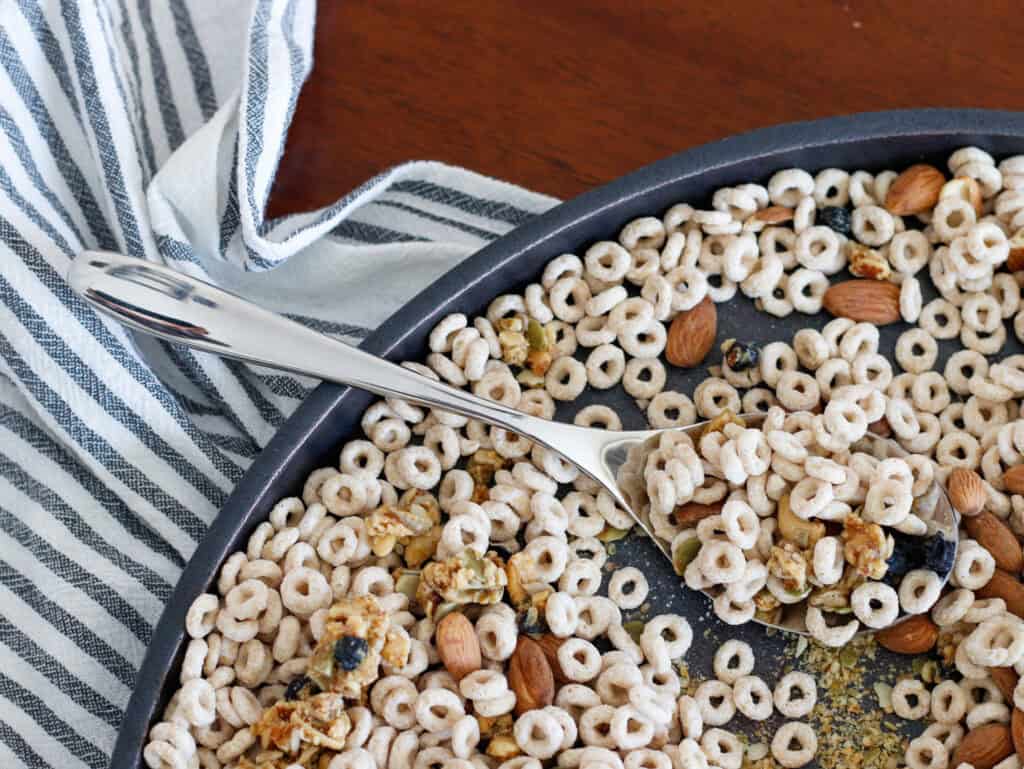 1. Close-up of a bowl of colorful cereal with nuts and dried fruit on a wooden table, with a striped cloth nearby.