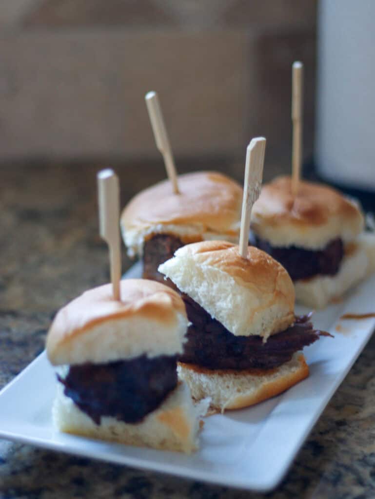 Cream-filled mini sliders with beef patties and soft buns on a white serving dish, ideal for gourmet food tasting, food photography, and appetizer presentation. Perfect for food lovers and culinary enthusiasts.