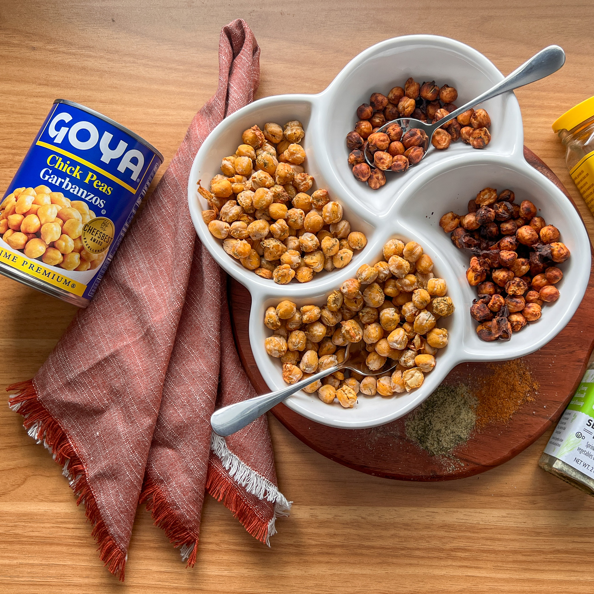 Overhead image of 4 flavor of air fried chickpeas in a serving bowl next to a can of Goya garbanzo beans