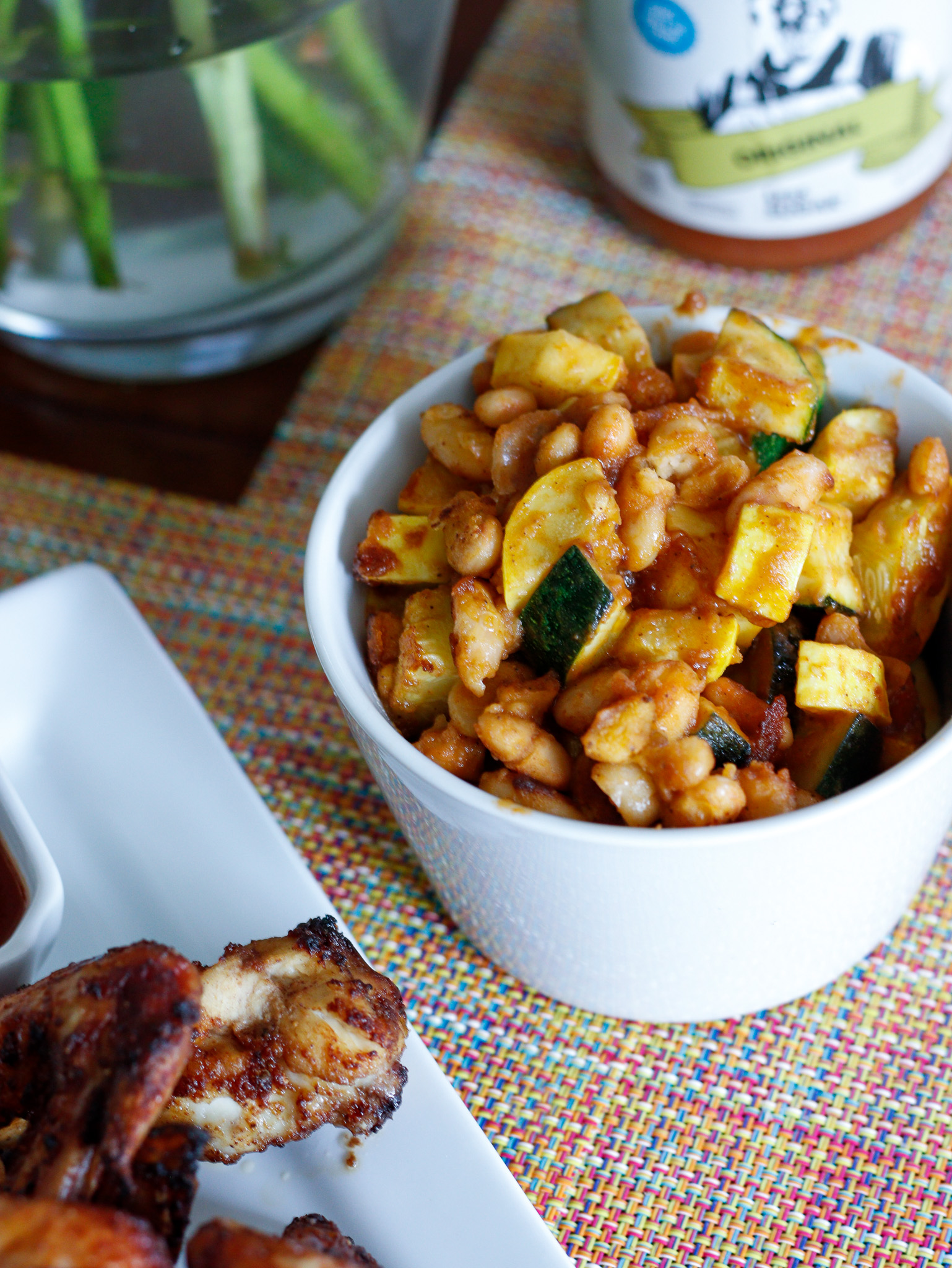 bowl of white beans and squash next to chicken wings